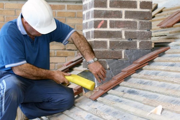 Roofer-repairing-flashing-around-chimney