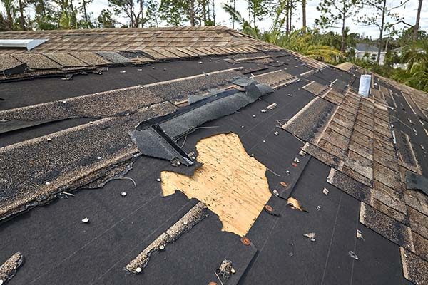 Damaged house roof with missing shingles after hurricane Ian in Florida. Consequences of natural disaster.